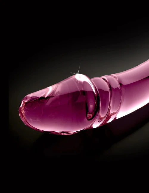 pink glass dildo head against black background