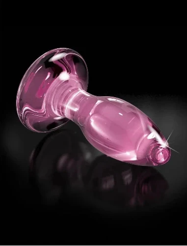 pink glass butt plug on black background