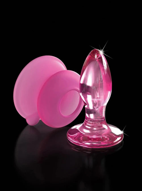 pink glass butt plug with pink silicone base next to it and black background
