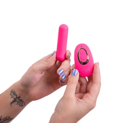 hands with purple nails holding pink vibrator and remote control
