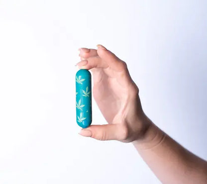 Hand holding Jessi bullet vibrator - emerald with hemp leaf print against white background