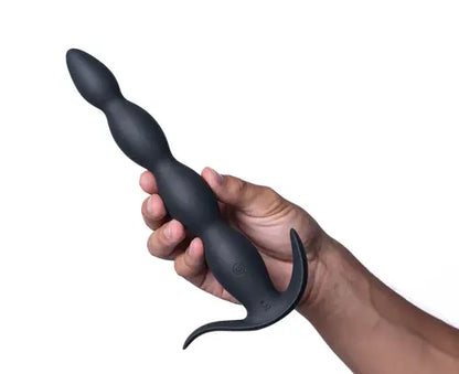 Hand holding MASON black beaded butt plug against white background