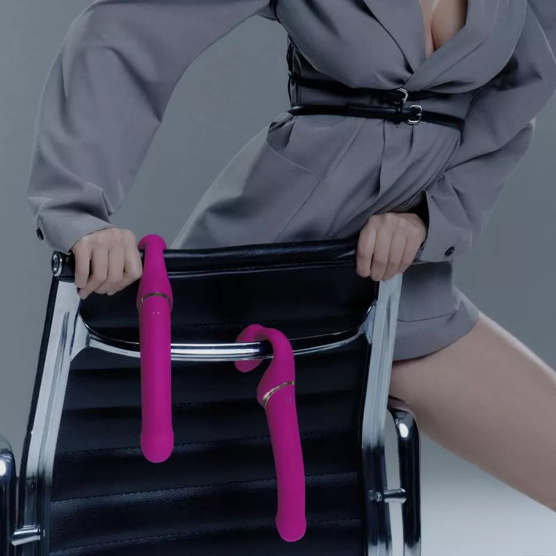 woman holding two strap on strapless fuchsia dildos