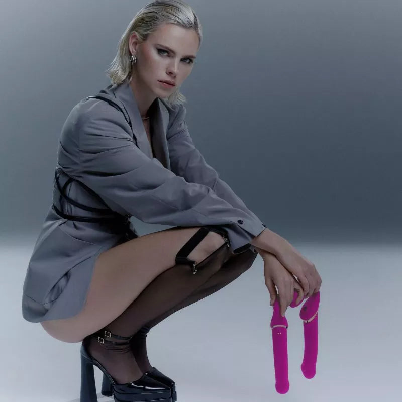 woman holding two fuchsia strapless strap ons